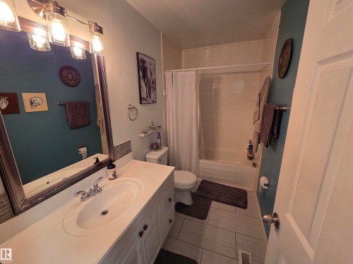 Full bathroom featuring a single vanity with a white countertop, undermount sink, and chrome faucet - 2514 149 Avenue, Edmonton, AB 