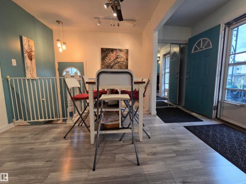 Entryway featuring two teal paneled doors with arch-top window details, light wood-finish flooring, and a mirrored closet - 2514 149 Avenue, Edmonton, AB 