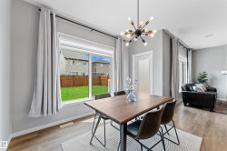 Dining area featuring a modern sputnik chandelier, wood-finish flooring, and a large window overlooking the backyard - 