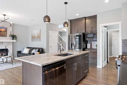 Open-concept kitchen featuring an island with a light-toned countertop and dual basin sink - 9664 223 Street, Edmonton, AB 