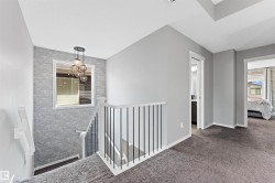 Stairwell featuring a contemporary chandelier, textured wall accent, and white window frame - 