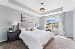 Bright bedroom featuring a tray ceiling, large window, and recessed lighting - 