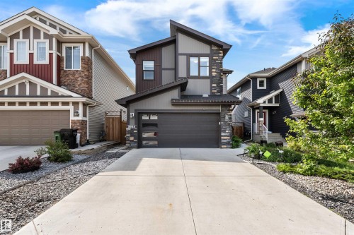 Contemporary two-story exterior featuring a multi-textured facade with stone accents, dark siding, and light gray panels - 9664 223 Street, Edmonton, AB 