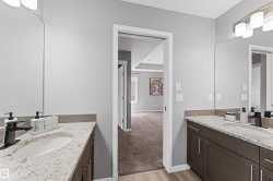 Dual vanity featuring light-toned countertops, integrated sinks, dark wood-finish cabinetry, and matte black faucets - 