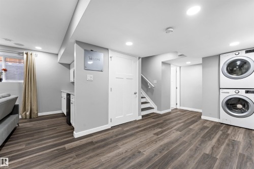 Finished lower level featuring wood-finish flooring, recessed lighting, and a built-in laundry center with stacked appliances - 9664 223 Street, Edmonton, AB 