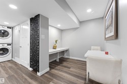 Dedicated laundry area featuring stacked appliances and wood-finish flooring - 