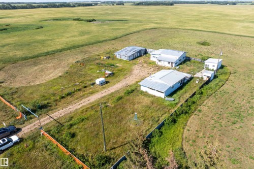 Expansive rural property featuring multiple outbuildings with metal roofs, a graded dirt driveway, and surrounding green fields - 534072 Range Road 85, Rural Two Hills County, AB 