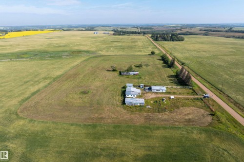 Expansive agricultural property featuring multiple structures, a gravel road, and extensive cultivated fields - 534072 Range Road 85, Rural Two Hills County, AB 