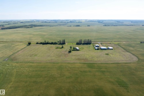 Expansive agricultural property featuring multiple outbuildings, cultivated fields, and a tree line - 534072 Range Road 85, Rural Two Hills County, AB 