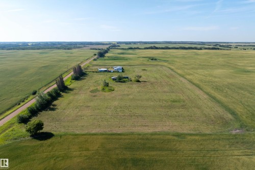 Rural property featuring a white residence, outbuildings, and expansive green fields under a clear sky - 534072 Range Road 85, Rural Two Hills County, AB 