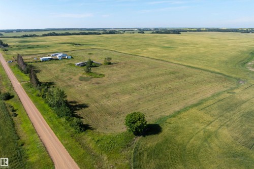 Expansive agricultural property featuring multiple detached structures, a private dirt road, and mature tree lines - 534072 Range Road 85, Rural Two Hills County, AB 