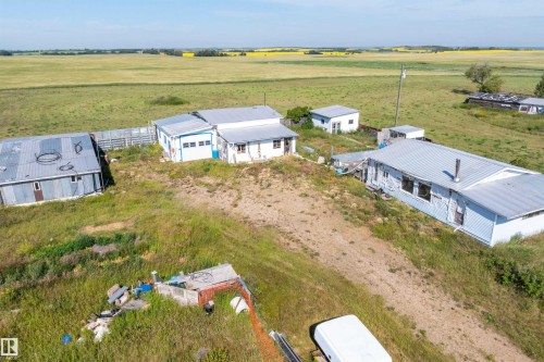 Multiple structures featuring metal roofs and light-colored siding, surrounded by expanses of green fields - 534072 Range Road 85, Rural Two Hills County, AB 