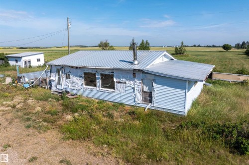 Single-story structure with a metal roof and light blue siding, situated on an expansive grassy lot - 534072 Range Road 85, Rural Two Hills County, AB 