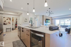 Modern kitchen island featuring a sink with a matte black faucet, integrated dishwasher, and a built-in wine cooler - 
