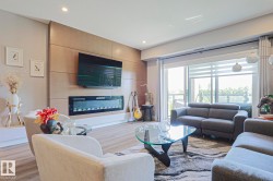 Spacious living area featuring wood-finish flooring and a wood-paneled accent wall with a built-in linear electric fireplace - 