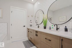 Dual vanity with integrated sinks, light wood-finish cabinetry, and black hardware - 