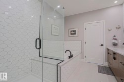 Contemporary bathroom featuring a frameless glass shower enclosure, a built-in tub with matte black fixtures, and a vanity with multiple storage drawers - 