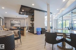 Spacious communal area featuring light wood-finish flooring, recessed lighting, and a prominent glass wall - 