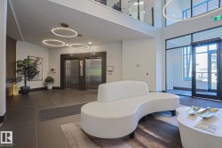 Lobby entrance featuring dual stainless steel elevators, dark large-format tile flooring, and a two-story ceiling - 