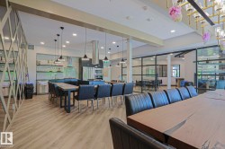 Spacious communal kitchen and dining area featuring wood-finish flooring, recessed lighting, and multiple pendant light fixtures - 
