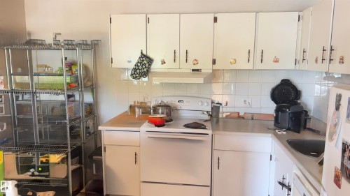 Kitchen featuring white cabinetry, white tile backsplash, and a white electric range - 311 8604 Gateway Boulevard, Edmonton, AB 