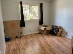 Room featuring wood-finish flooring, light grey painted walls, and a large window with white trim - 
