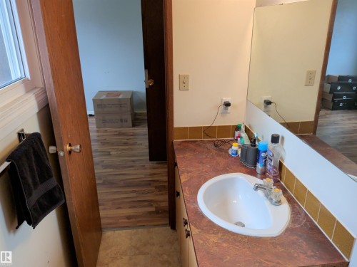 Bathroom vanity with an integrated white sink and a brown-toned countertop, featuring a large wall-mounted mirror - 2724 105 Street Nw, Edmonton, AB - Indoor Photo Showing Bathroom