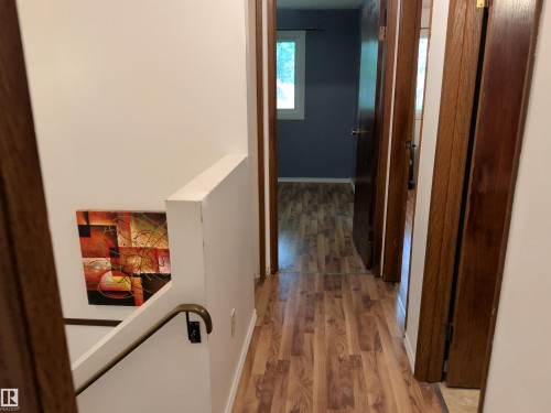 Hallway featuring wood-finish flooring, white walls, and dark wood-stained interior doors - 2724 105 Street Nw, Edmonton, AB - Indoor Photo Showing Other Room