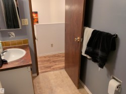 Vanity featuring a white basin sink, polished chrome faucet, and brown countertop - 