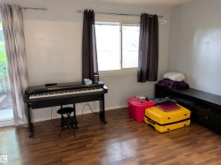 Room featuring wood-finish flooring, a double window, and a sliding glass door - 