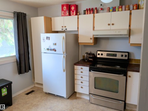 Kitchen featuring white cabinetry, a built-in range hood, a stainless steel range, and wood-finish countertops - 2724 105 Street Nw, Edmonton, AB - Indoor Photo Showing Kitchen