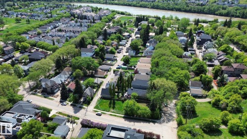 Aerial perspective showcasing a residential area with varied housing styles, mature tree canopies, and a prominent riverine setting - 10173 93 Street, Edmonton, AB 