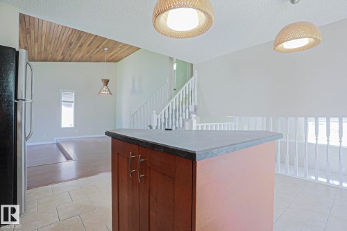 Kitchen island with wood cabinetry and stone-finish countertop - 17811 62C Avenue, Edmonton, AB 