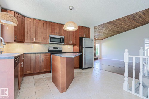 Kitchen featuring wood-finish cabinetry, stainless steel appliances, and an island with a countertop - 17811 62C Avenue, Edmonton, AB 