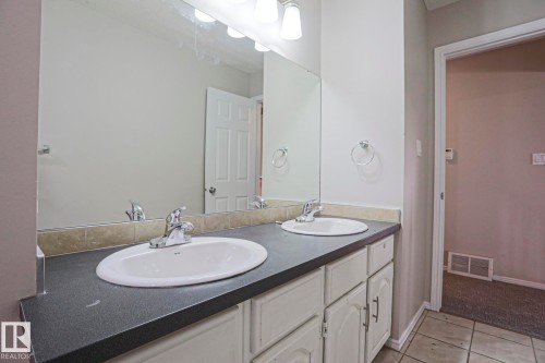 Double vanity with dual undermount sinks, chrome faucets, and a dark countertop - 17811 62C Avenue, Edmonton, AB 