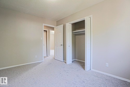 Neutral-toned room featuring light gray walls, white baseboards, and textured carpeting - 17811 62C Avenue, Edmonton, AB 