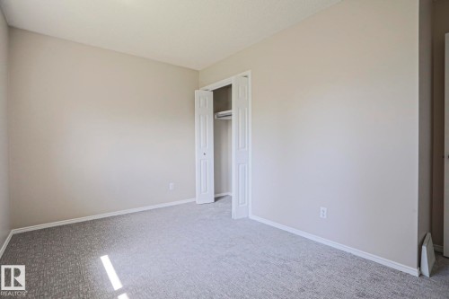 Neutral-toned room featuring light gray walls, white baseboards, and a textured gray carpet - 17811 62C Avenue, Edmonton, AB 