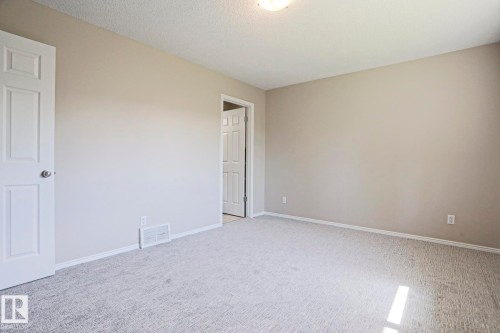 Carpeted room featuring light gray walls, white baseboards, and a textured ceiling - 17811 62C Avenue, Edmonton, AB 