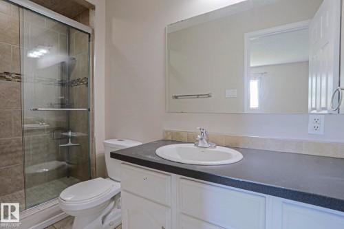 Bathroom featuring a glass-enclosed shower with tile surround, mosaic accent band, and built-in shelving - 17811 62C Avenue, Edmonton, AB 