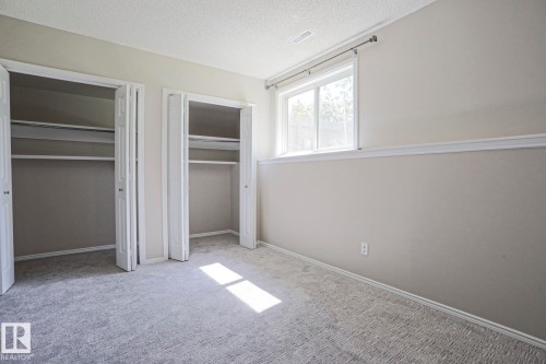 Plush gray carpeting throughout, featuring two bi-fold door closets with integrated shelving and hanging rods - 17811 62C Avenue, Edmonton, AB 
