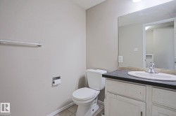 Bathroom featuring a white toilet, light-toned wall paint, and a vanity with a dark countertop and integrated sink - 