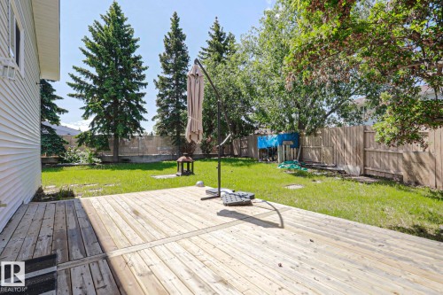 Spacious outdoor wooden deck overlooking a grassy yard, featuring mature trees and wood fencing - 17811 62C Avenue, Edmonton, AB 