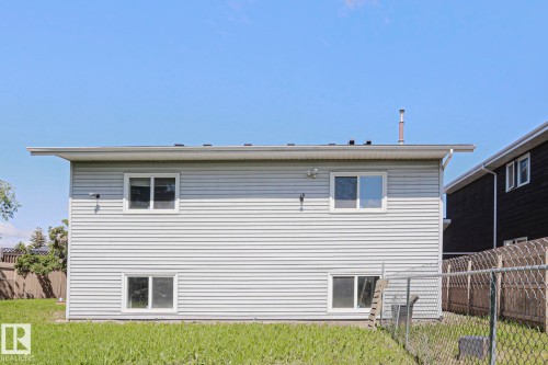 Rear elevation with light gray horizontal siding, white trim windows, and a green lawn - 17811 62C Avenue, Edmonton, AB 