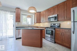 Kitchen featuring wood-finish cabinetry, stainless steel appliances, and a central island with countertop space - 