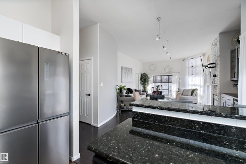 Recently renovated kitchen featuring freestanding refrigerator, dark wood-style floors, open floor plan, and white cabinets - 302 10905 109 Street, Edmonton, AB 