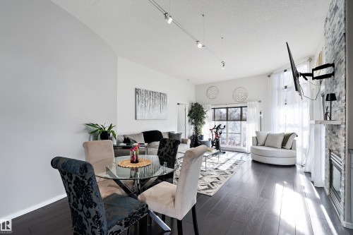 Dining room featuring dark wood-style floors, a fireplace, a textured ceiling, and track lighting - 302 10905 109 Street, Edmonton, AB 