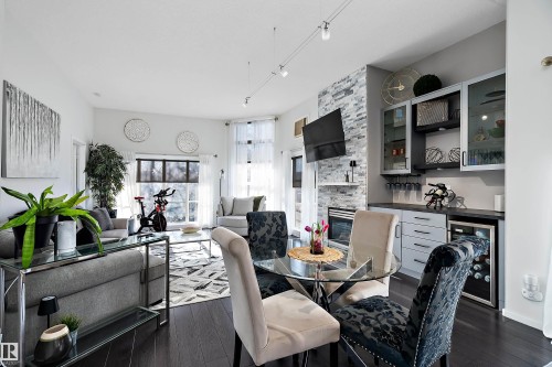Dining room with a fireplace, wine cooler, dark wood-type flooring, and track lighting - 302 10905 109 Street, Edmonton, AB 