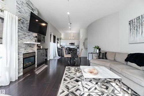 Living room featuring dark wood-type flooring and a stone fireplace - 302 10905 109 Street, Edmonton, AB 