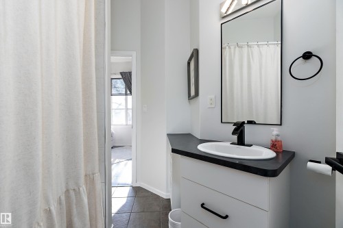 Full bath with vanity, a shower with shower curtain, and dark tile patterned floors - 302 10905 109 Street, Edmonton, AB 