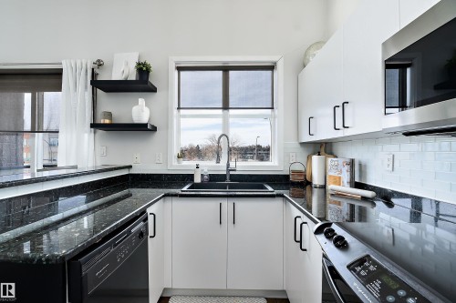 Recently renovated kitchen  featuring dark stone countertops, stainless steel appliances, white cabinetry, and open shelves - 302 10905 109 Street, Edmonton, AB 